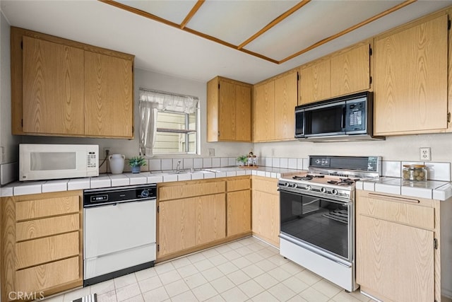 kitchen with tile counters, white appliances, a sink, and light brown cabinetry