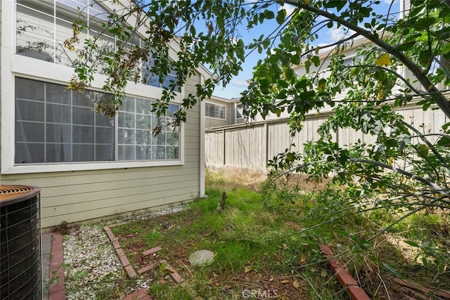 view of yard featuring fence and central air condition unit