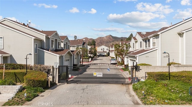 view of road featuring a residential view, a gate, a gated entry, and curbs