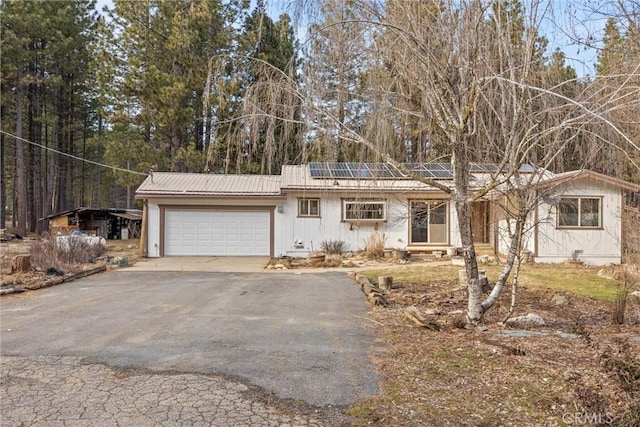 ranch-style home with solar panels, crawl space, metal roof, a garage, and driveway