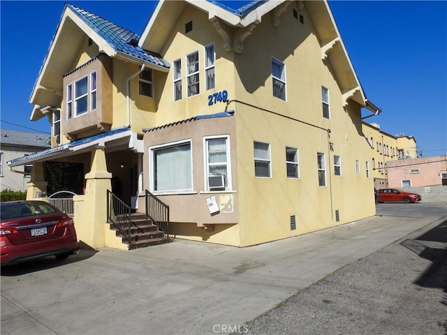 exterior space featuring a tiled roof, cooling unit, and stucco siding