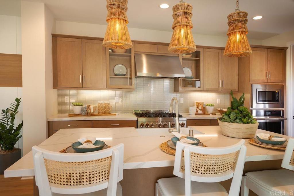 kitchen with tasteful backsplash, appliances with stainless steel finishes, pendant lighting, and exhaust hood