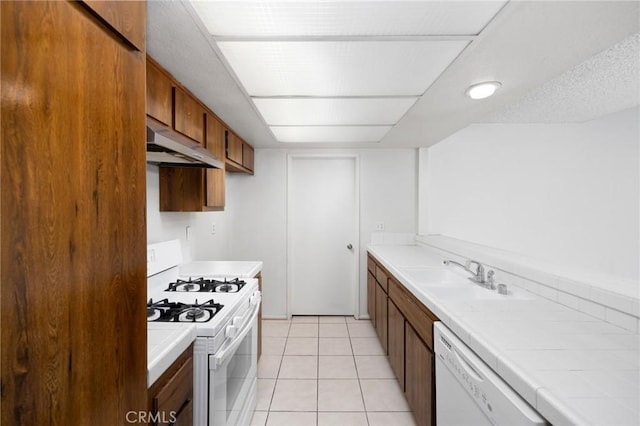 kitchen with tile countertops, extractor fan, white appliances, a sink, and brown cabinetry