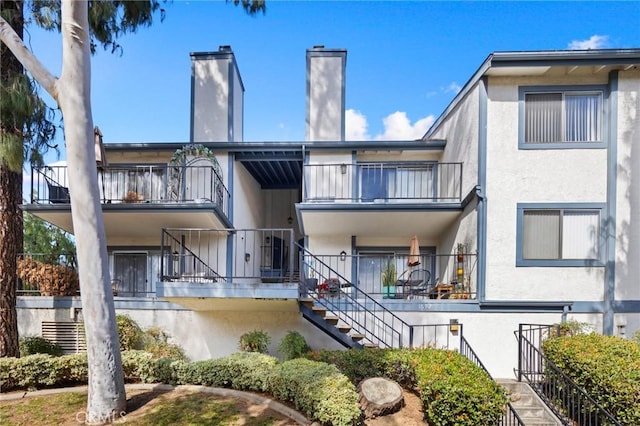 1694 Bridgeport, West Covina, CA 91791 - rear view of property featuring stairs, a balcony, a chimney, and stucco siding