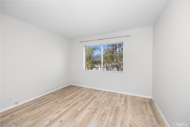 spare room featuring baseboards and light wood-style floors