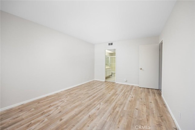 empty room featuring baseboards, visible vents, and light wood finished floors