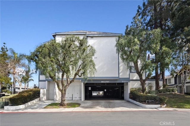 view of front of home with an attached garage, concrete driveway, and stucco siding