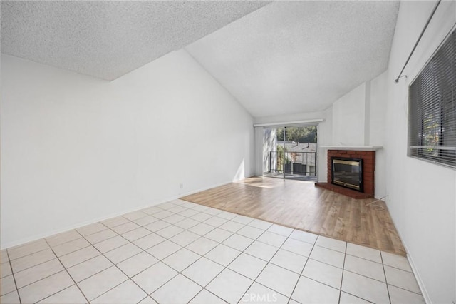 unfurnished living room featuring lofted ceiling, a fireplace, a textured ceiling, and light tile patterned flooring