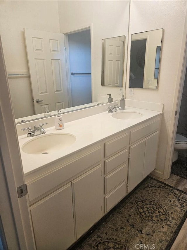 full bathroom with double vanity, a sink, and toilet