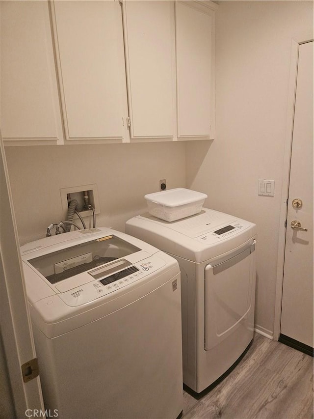 laundry area with cabinet space, washer and clothes dryer, and light wood finished floors