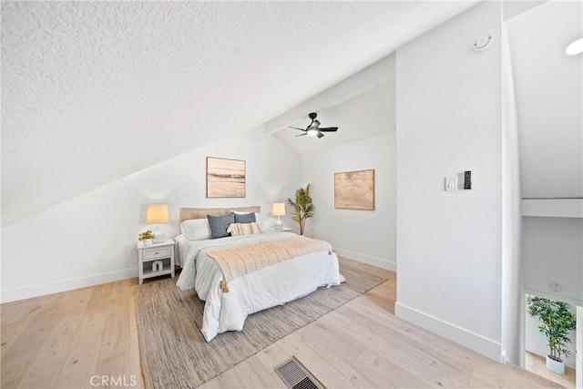 bedroom featuring light wood-type flooring, baseboards, vaulted ceiling, and a textured ceiling