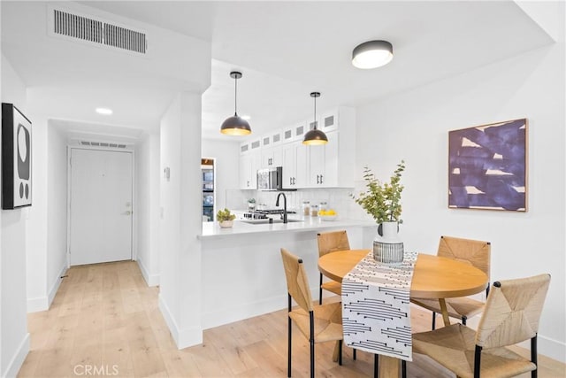 dining space with light wood-type flooring, visible vents, and baseboards