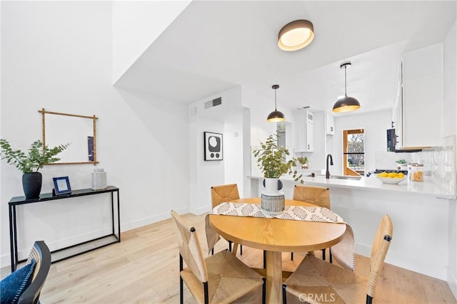 dining space featuring light wood-type flooring, baseboards, and visible vents