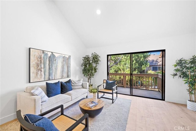 living area featuring high vaulted ceiling, baseboards, and light wood finished floors