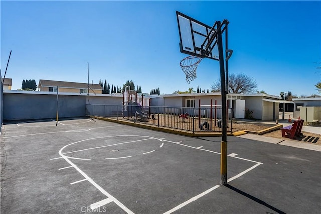 view of basketball court featuring community basketball court, fence, and playground community