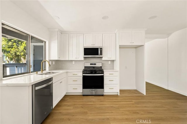 kitchen with stainless steel appliances, light countertops, a sink, and white cabinetry