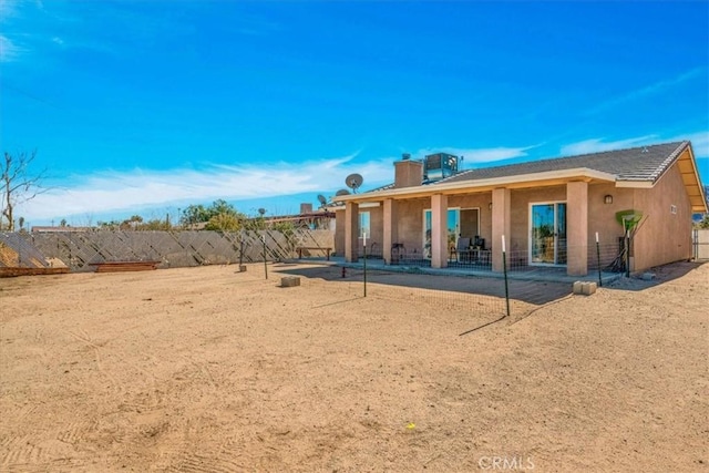 rear view of property featuring stucco siding, a chimney, and fence