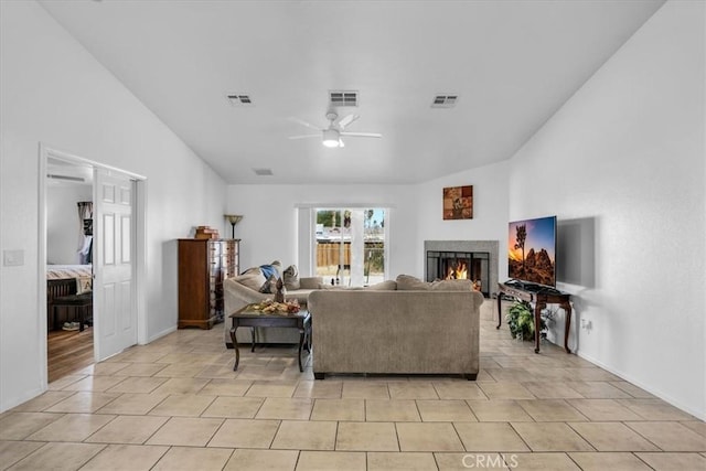 living room featuring light tile patterned flooring, a ceiling fan, visible vents, and a lit fireplace