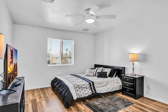 bedroom with visible vents, wood finished floors, baseboards, and ceiling fan