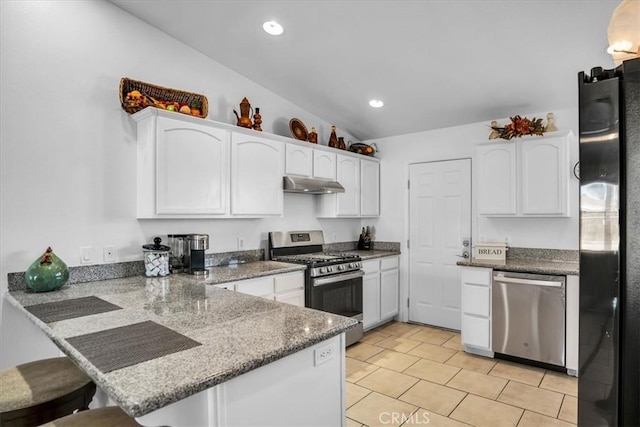 kitchen with a peninsula, under cabinet range hood, appliances with stainless steel finishes, white cabinetry, and a kitchen breakfast bar