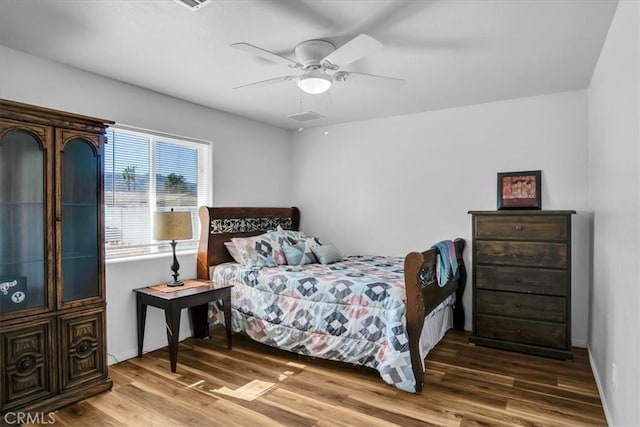 bedroom featuring a ceiling fan, wood finished floors, visible vents, and baseboards