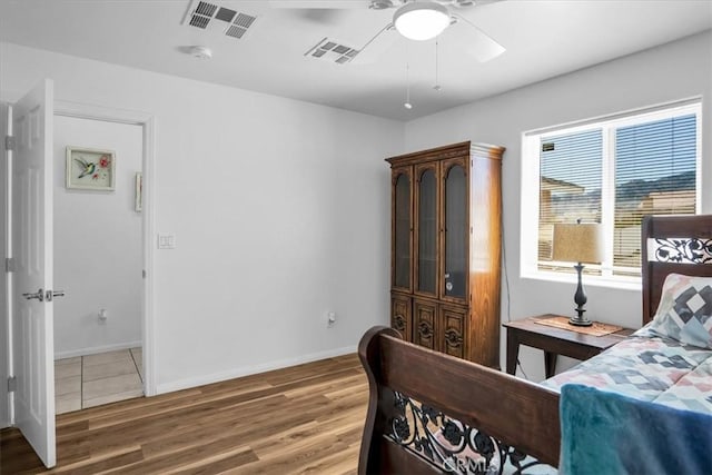 bedroom with visible vents, a ceiling fan, baseboards, and wood finished floors