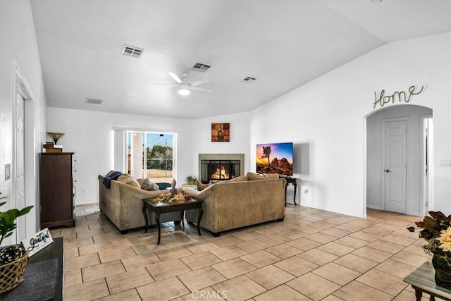 living room featuring visible vents, a lit fireplace, lofted ceiling, light tile patterned floors, and a ceiling fan