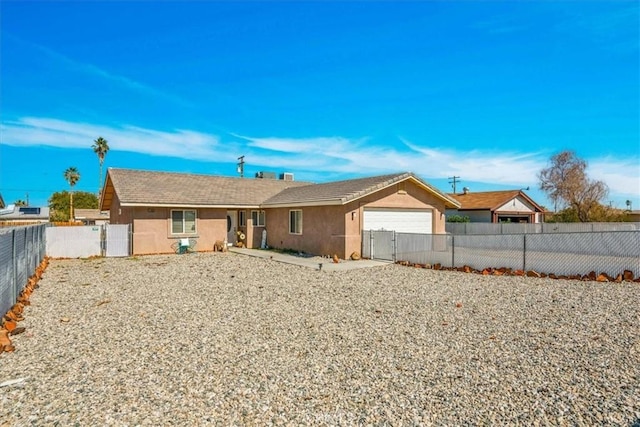 rear view of house featuring stucco siding, driveway, fence private yard, and a garage