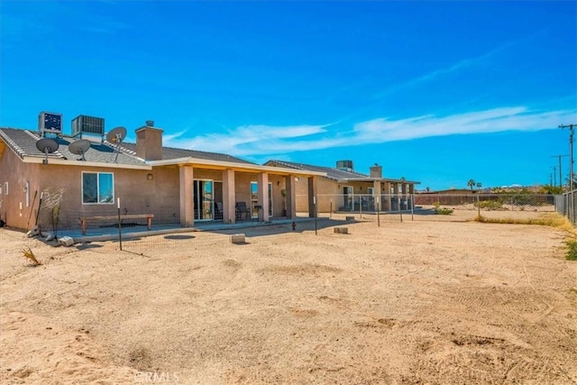 back of property with a patio area, stucco siding, a chimney, and fence