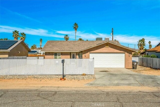 single story home featuring driveway, a fenced front yard, an attached garage, and stucco siding