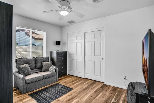 living area featuring visible vents, baseboards, a ceiling fan, and wood finished floors