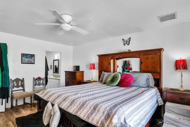 bedroom with light wood finished floors, visible vents, ensuite bathroom, and a ceiling fan