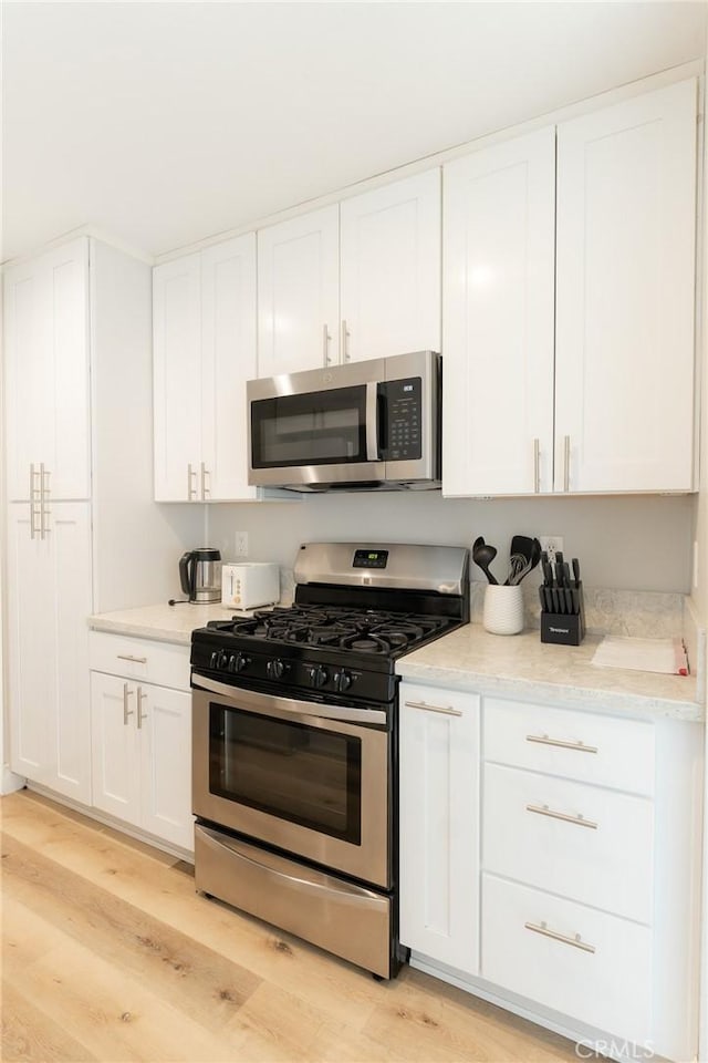 kitchen featuring appliances with stainless steel finishes, white cabinetry, and light wood finished floors