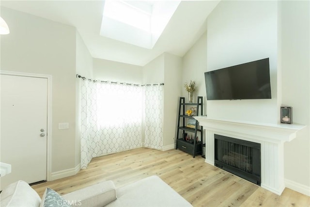 living area with lofted ceiling, light wood finished floors, a fireplace, and baseboards