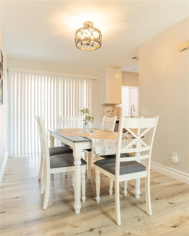 dining space with visible vents, light wood-style flooring, and baseboards