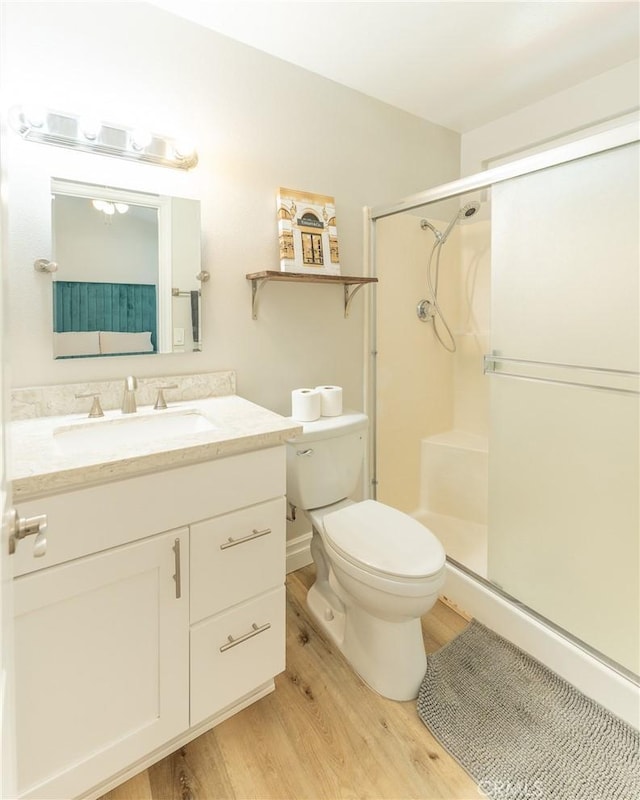 full bath with toilet, a stall shower, wood finished floors, and vanity