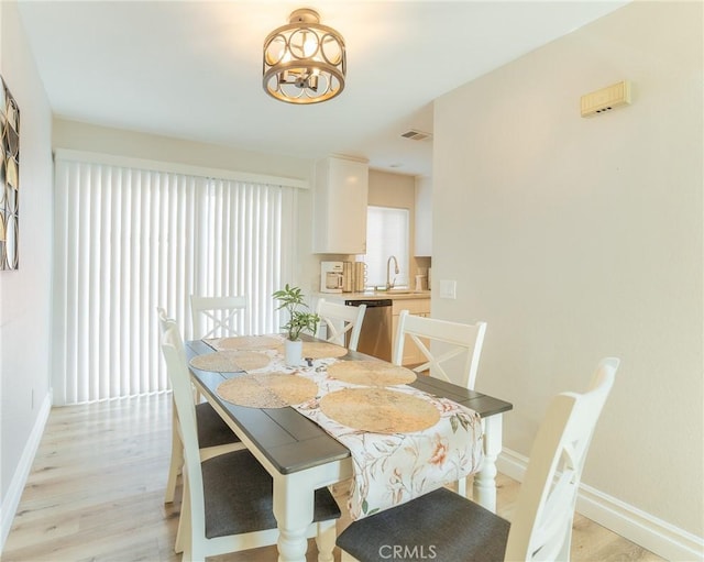 dining area with light wood finished floors, visible vents, and baseboards