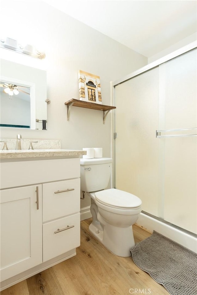 bathroom with a stall shower, vanity, toilet, and wood finished floors