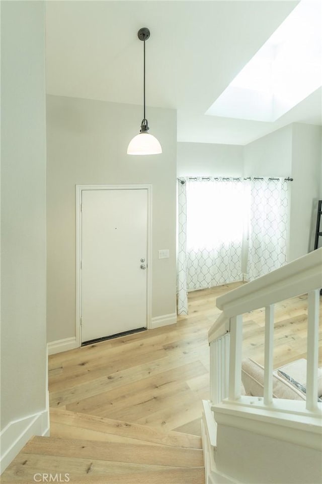 foyer entrance featuring a skylight, baseboards, and light wood finished floors