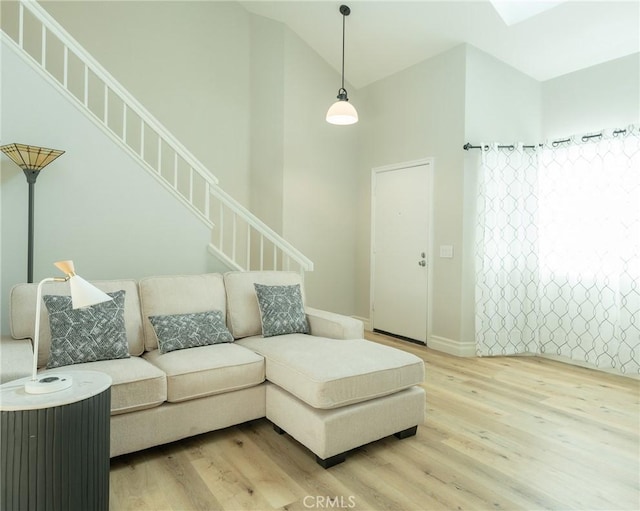 living area featuring stairs, high vaulted ceiling, baseboards, and wood finished floors