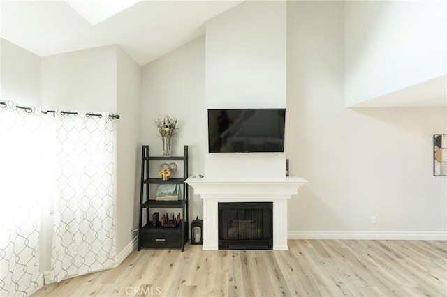 living room with lofted ceiling, a fireplace, baseboards, and light wood-style floors