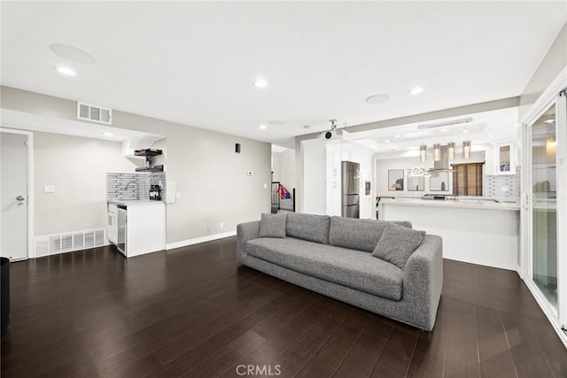 living area with dark wood-style floors, recessed lighting, visible vents, and baseboards