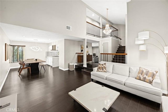 living area featuring stairs, dark wood-style floors, visible vents, and baseboards