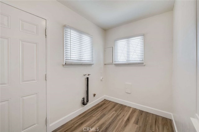 clothes washing area with gas dryer hookup, laundry area, baseboards, and wood finished floors