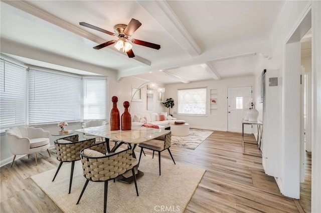 dining room featuring light wood-style floors, beamed ceiling, and baseboards