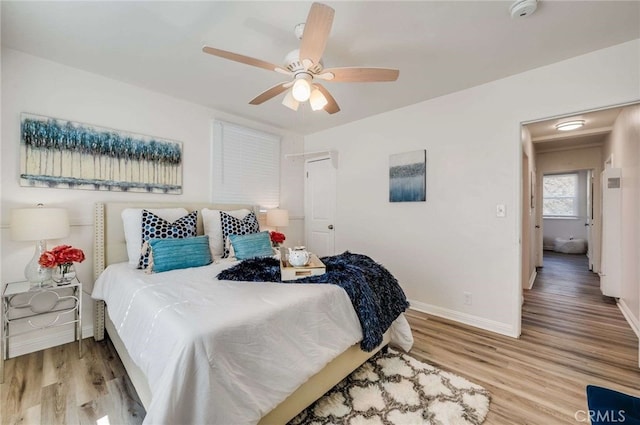 bedroom with a ceiling fan, light wood-style flooring, and baseboards