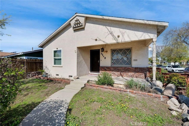 view of front of house with crawl space, fence, and stucco siding