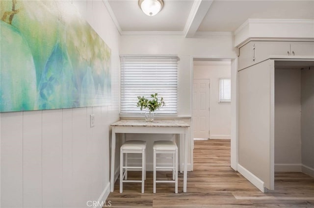 unfurnished dining area featuring ornamental molding, light wood-type flooring, and baseboards