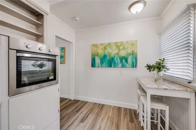 kitchen with baseboards, ornamental molding, oven, light wood-type flooring, and open shelves