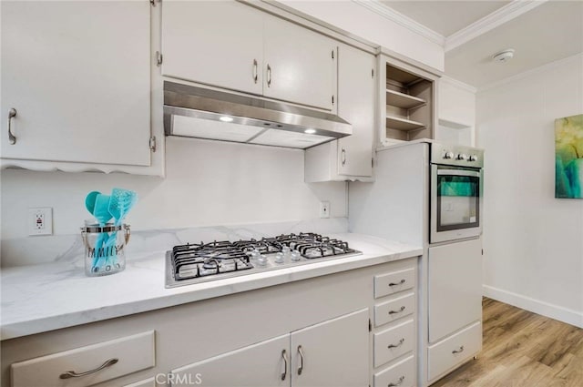 kitchen with ornamental molding, stainless steel appliances, light countertops, light wood-type flooring, and under cabinet range hood